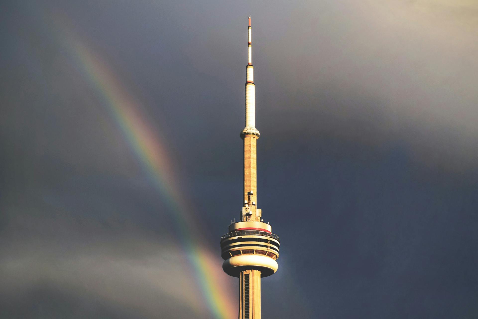 Stunning view of CN Tower with a rainbow against a moody sky in Toronto, Canada.