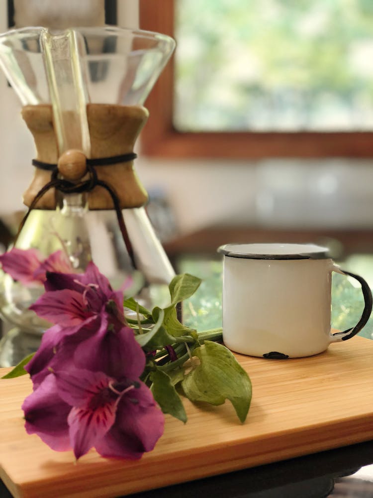 Flowers Near Glass Vase And Iron Mug On Table