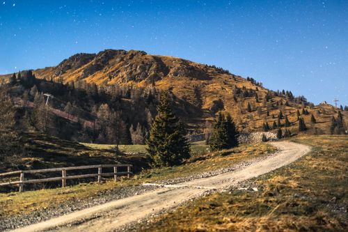 Free A serene night view of a dirt pathway winding through the Italian mountains under a starry sky. Stock Photo