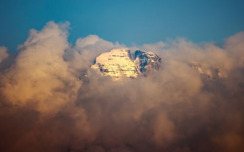 Free Majestic snowy mountain peak in Italy emerging from clouds under a blue sky. Stock Photo