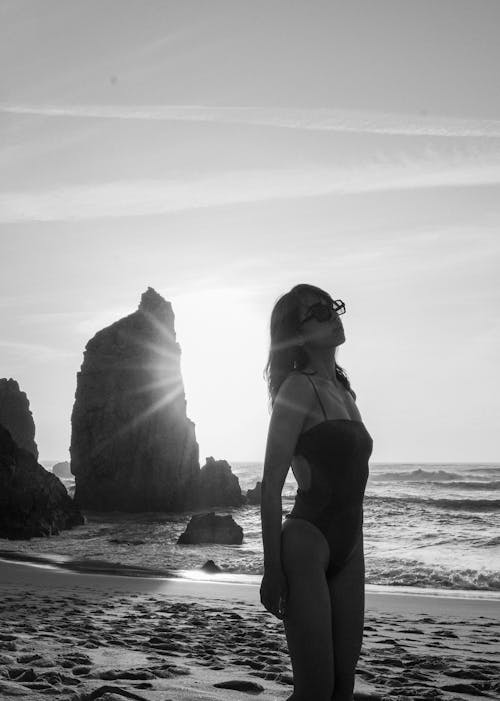 Black and White Back Lit Photograph of a Woman on a Sandy Beach