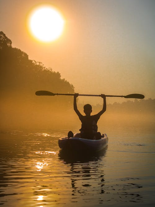 Silhouette of a Person Riding on Kayak during Sunset
