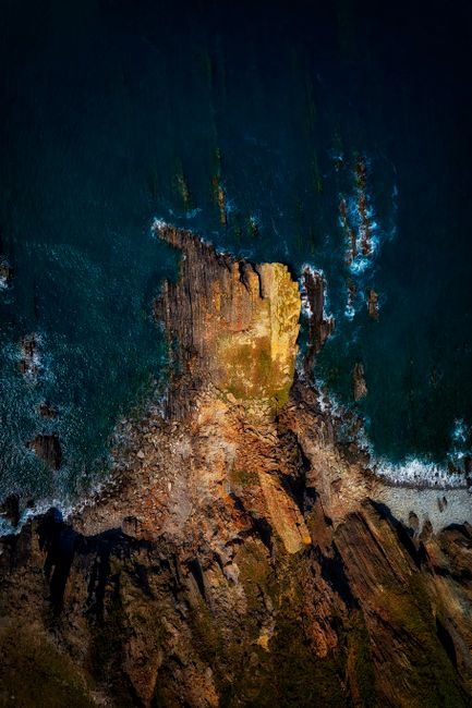 A stunning aerial view of rocky cliffs and ocean waves along the Hartland coastline in Devon, UK.