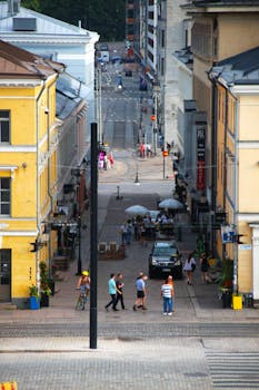 A bustling street in Helsinki with people walking and outdoor cafes, captured in summer.