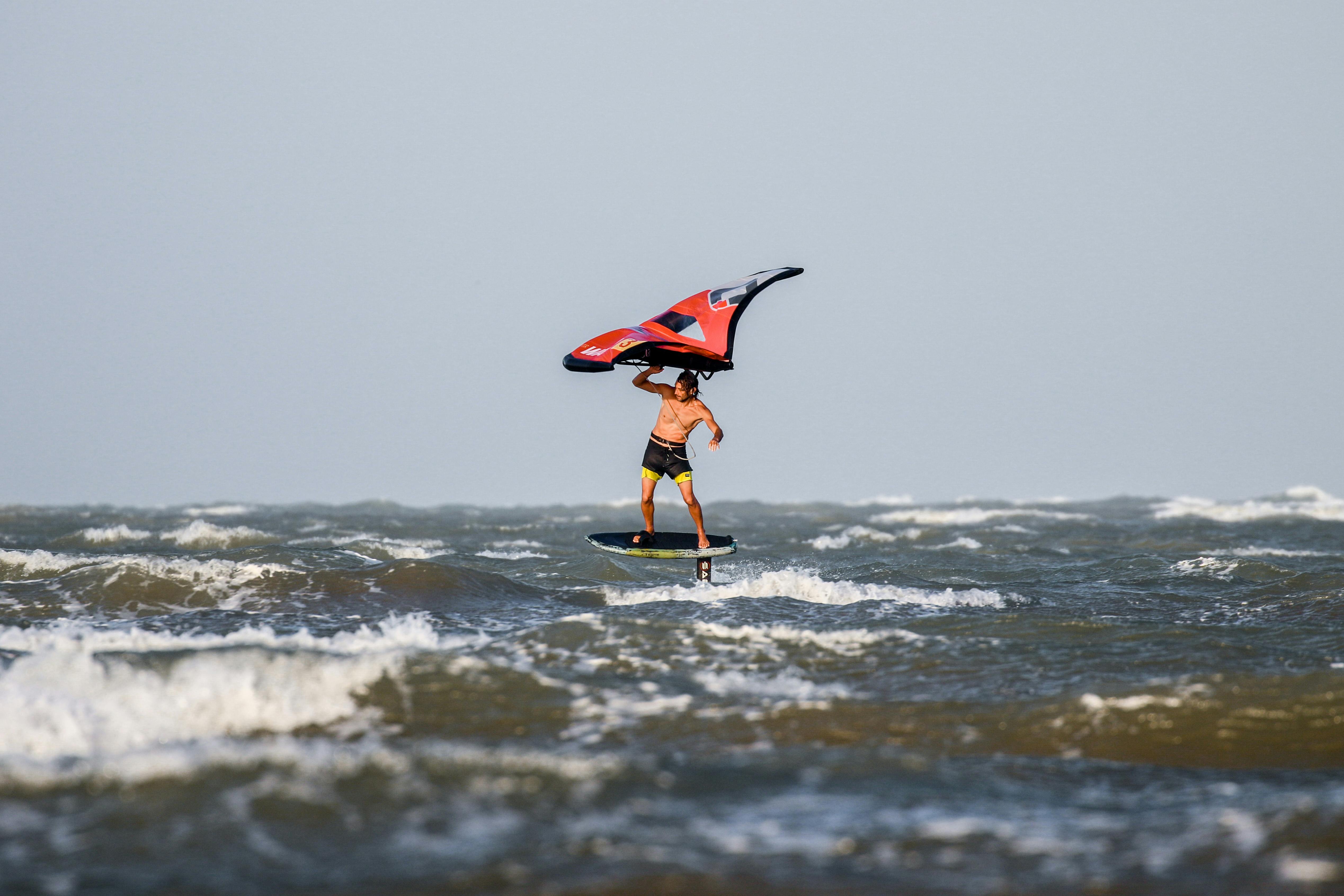 Man Windsurfing while Holding an Inflatable Kite · Free Stock Photo