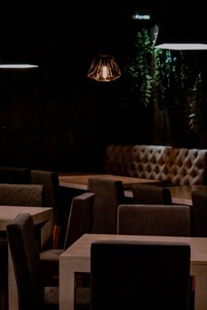 Dimly lit restaurant interior with modern decor and empty tables, offering a warm and inviting atmosphere.