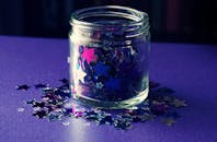 这个装满五颜六色星形五彩纸屑的紫色玻璃罐，非常适合用于工艺品和装饰