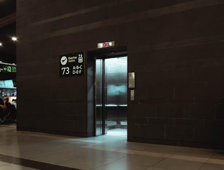 Open elevator in a modern airport terminal, showcasing sleek design and signage.