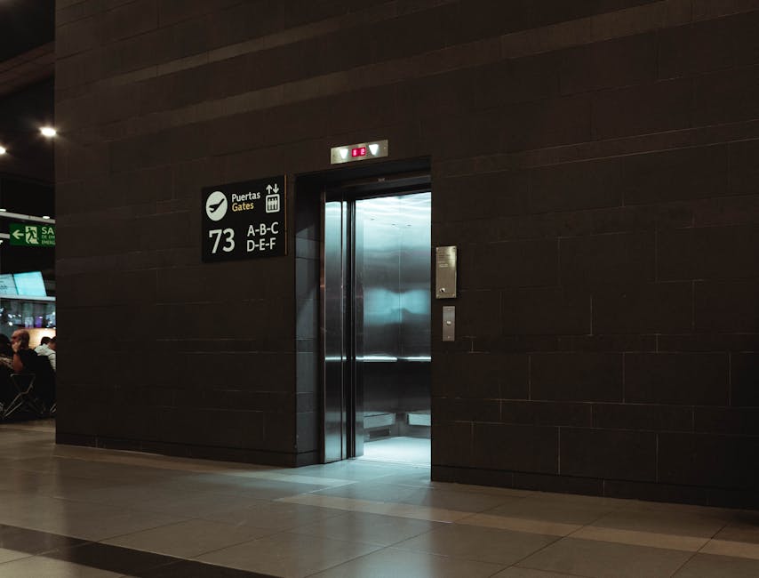 Open elevator in a modern airport terminal, showcasing sleek design and signage.