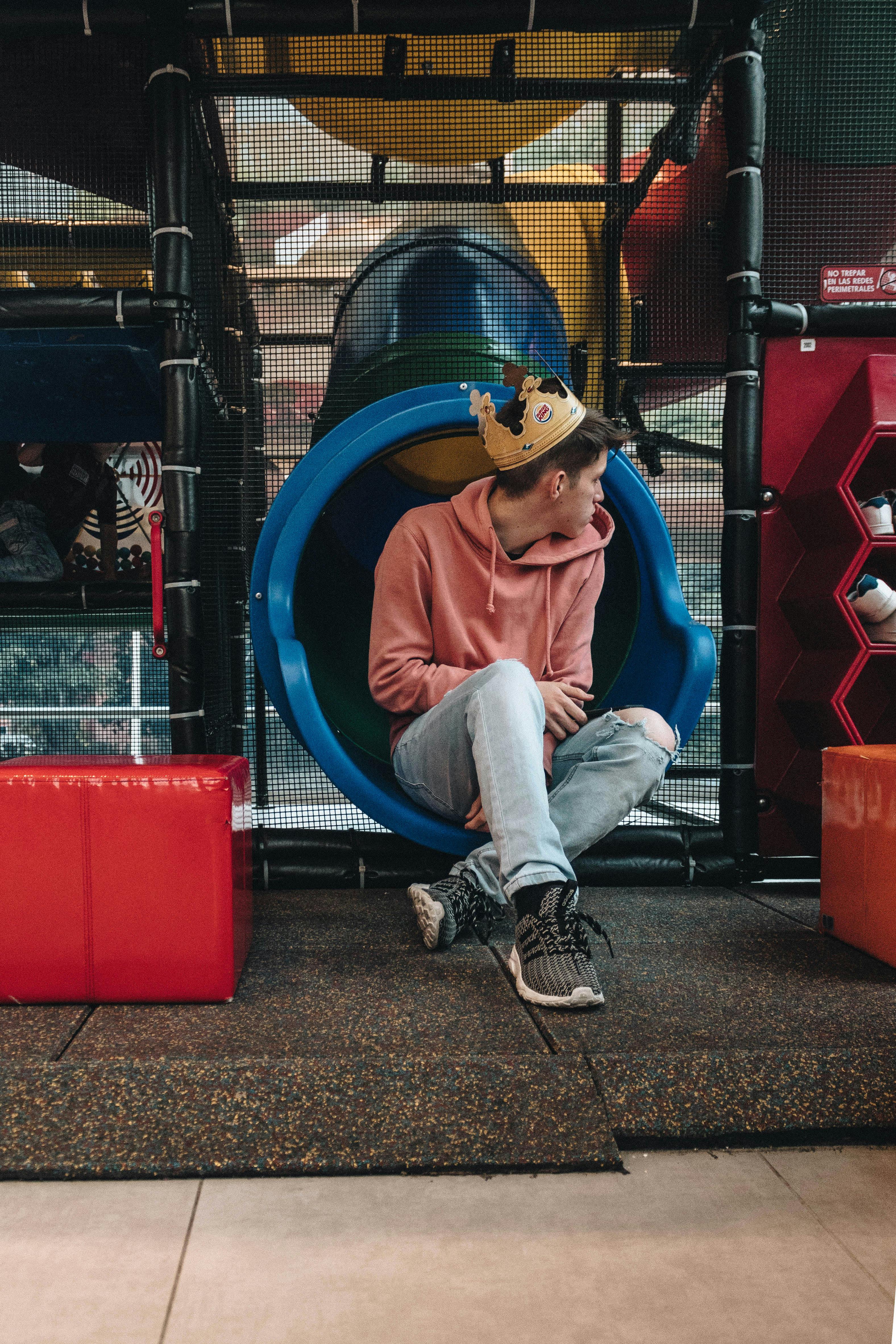 man in a pink hoodie sitting on a slide tube