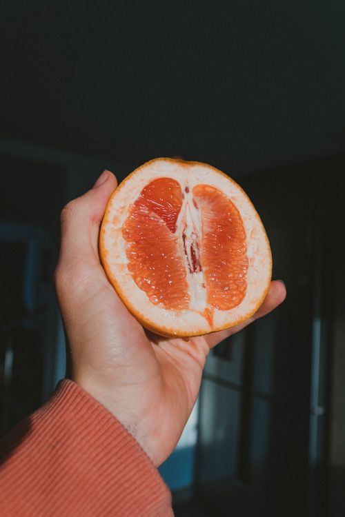 Free A person holding a sliced grapefruit in natural light, showcasing vibrant colors and texture. Stock Photo