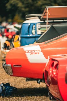 Close-up of a classic Yenko Deuce car in vibrant red at an outdoor automotive show.