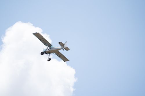 Free A small airplane soaring through blue sky with clouds, captured from below. Stock Photo