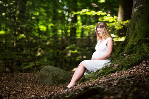 Free Woman in White Dress Sitting on Brown Rock Stock Photo