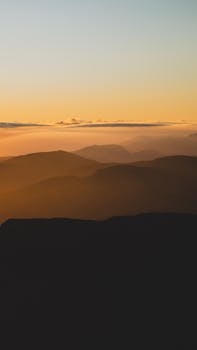 Peaceful mountain scape with a stunning sunset sky, perfect for tranquility and nature themes.