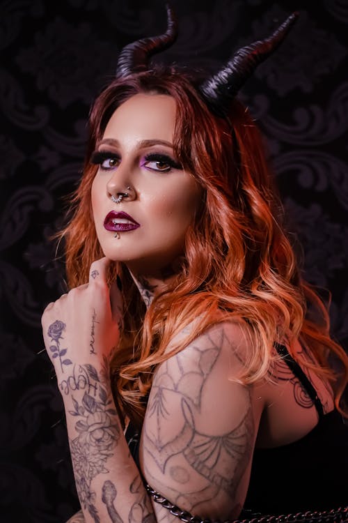 Portrait of a Young Tattooed Woman Wearing Devil Horns