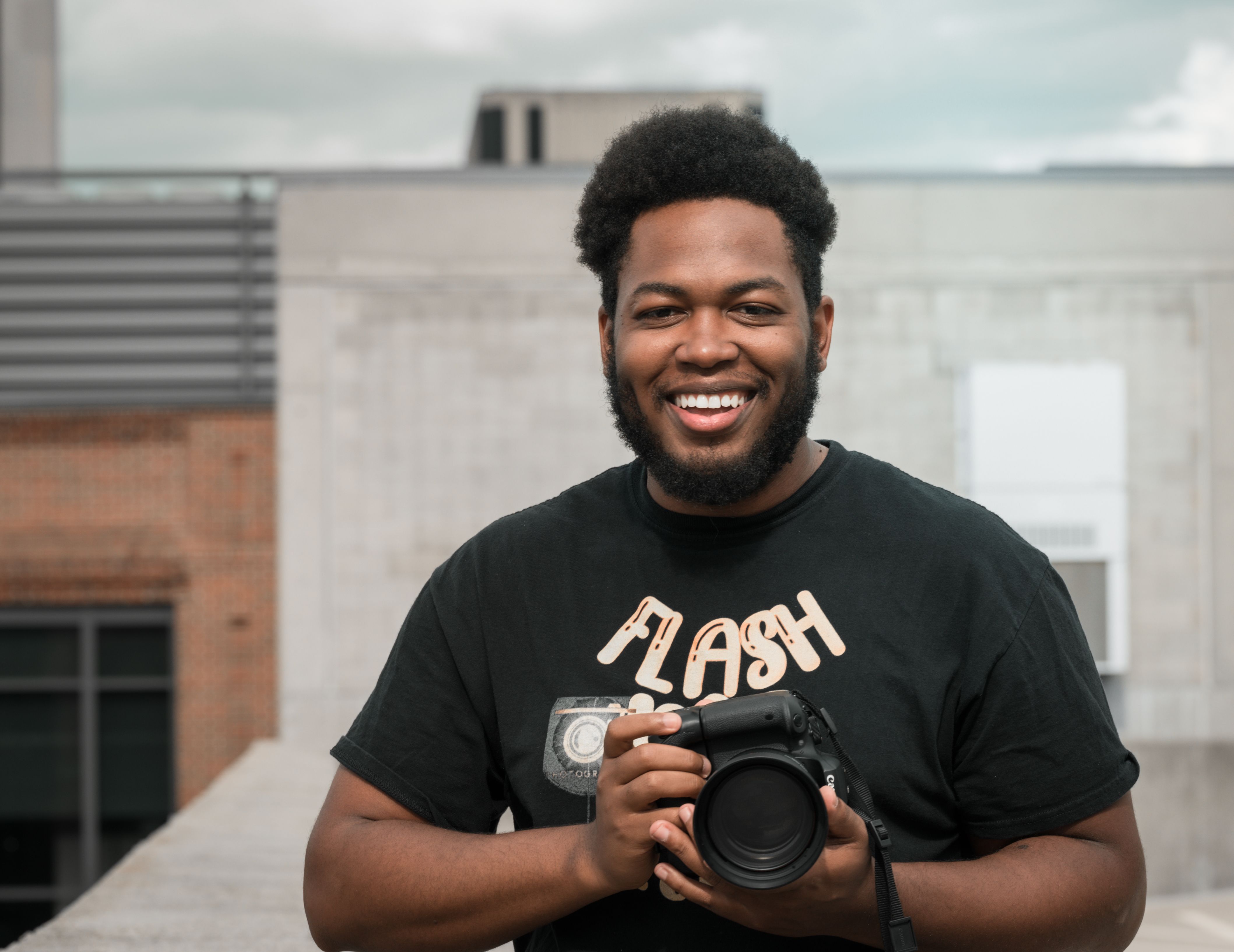 Portrait of a joyful photographer with a camera, ready for a photo shoot outdoors.