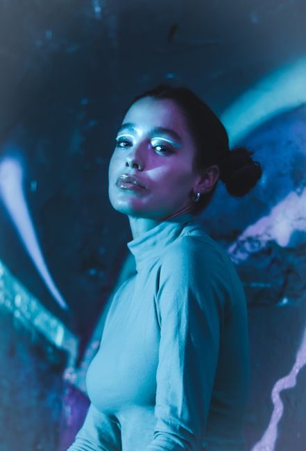 Artistic portrait of a woman with makeup in moody blue lighting.