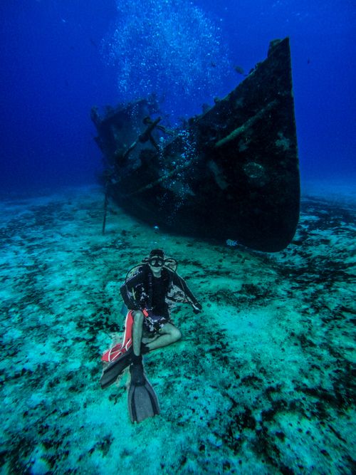 Free Scuba diver exploring a shipwreck in the clear waters off Cozumel, Mexico. An underwater adventure awaits. Stock Photo
