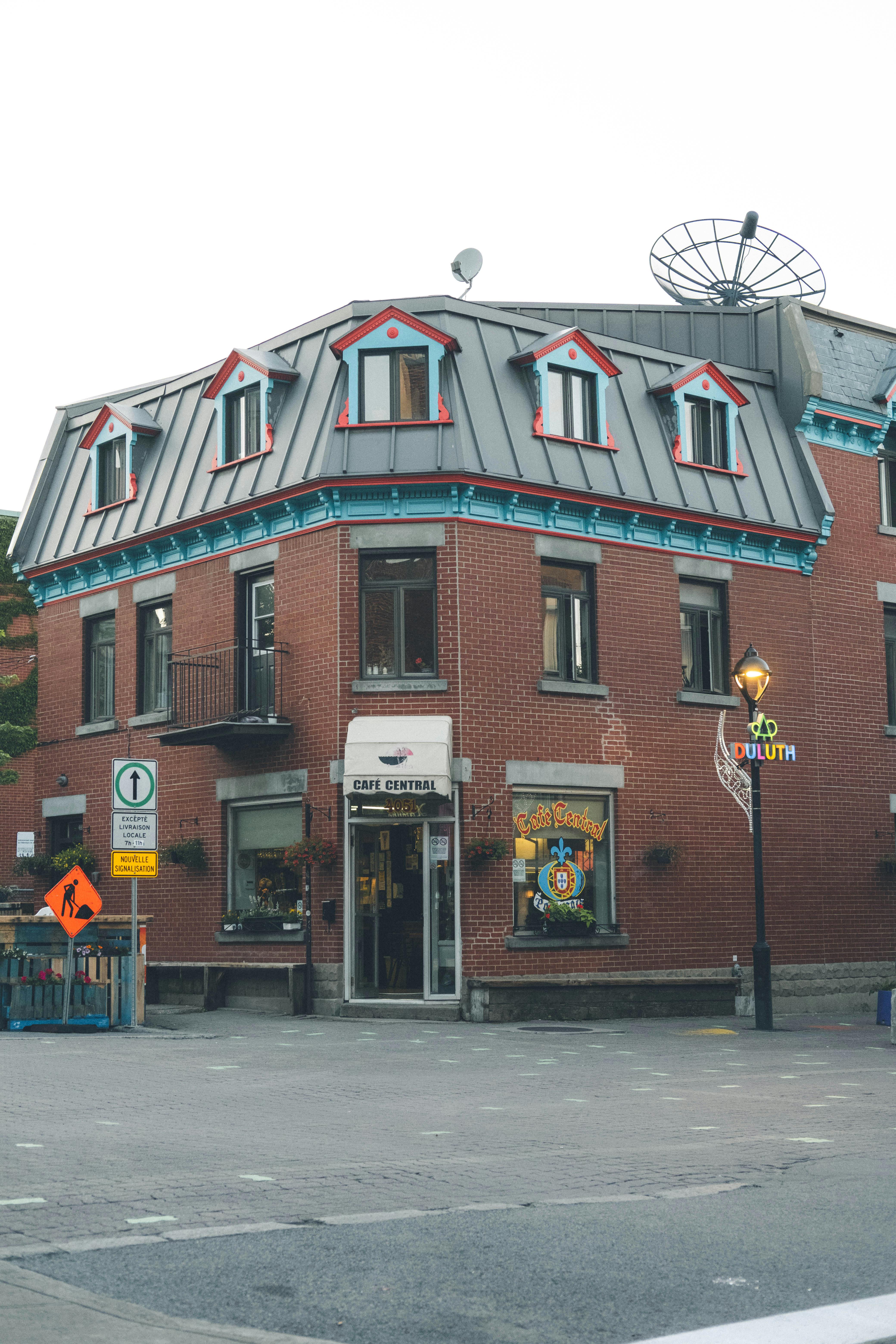 Free Charming corner building with distinct brick facade and colorful details in urban setting. Stock Photo