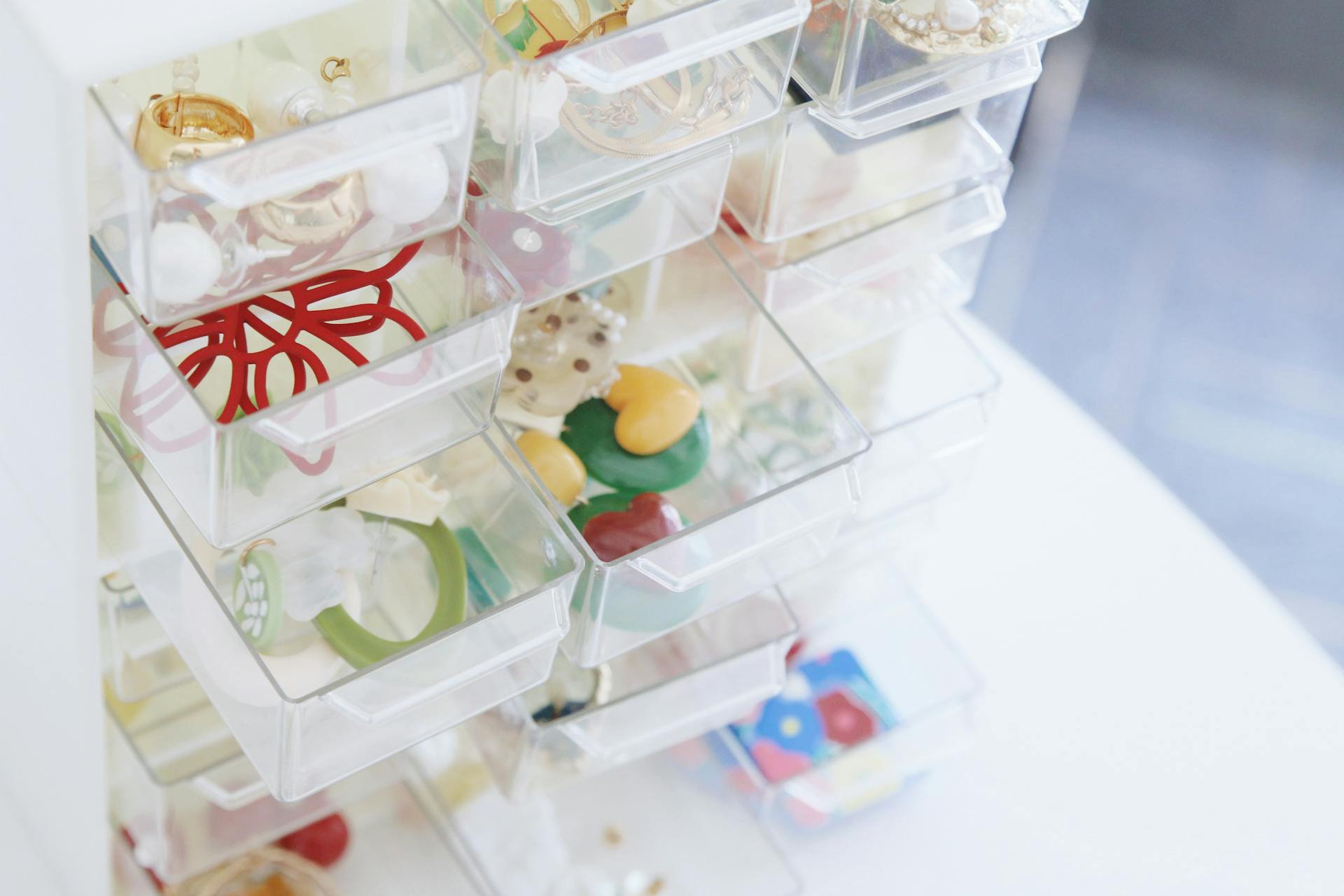 A collection of colorful jewelry pieces organized in transparent storage drawers.