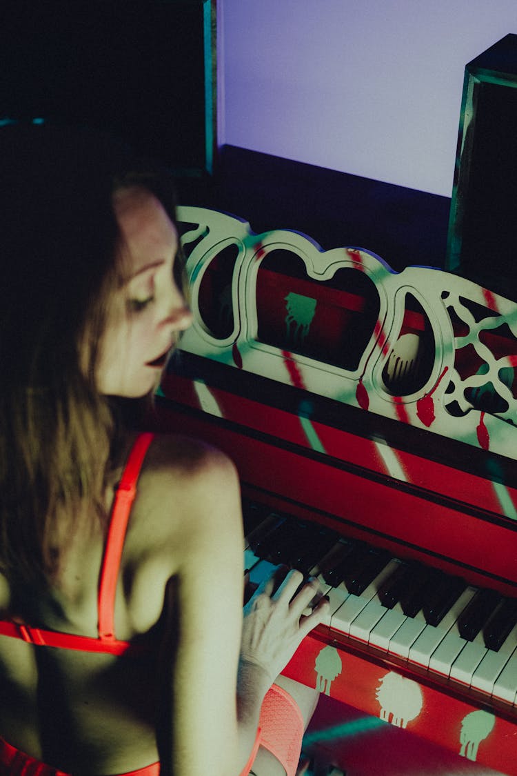 Over The Shoulder View Of A Young Shirtless Woman Playing Piano