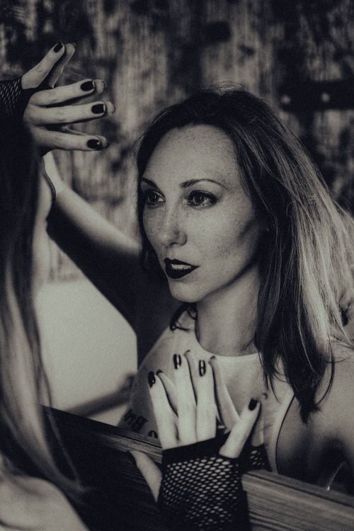 Free Elegant woman gazing intensely into a mirror in this black and white portrait. Stock Photo