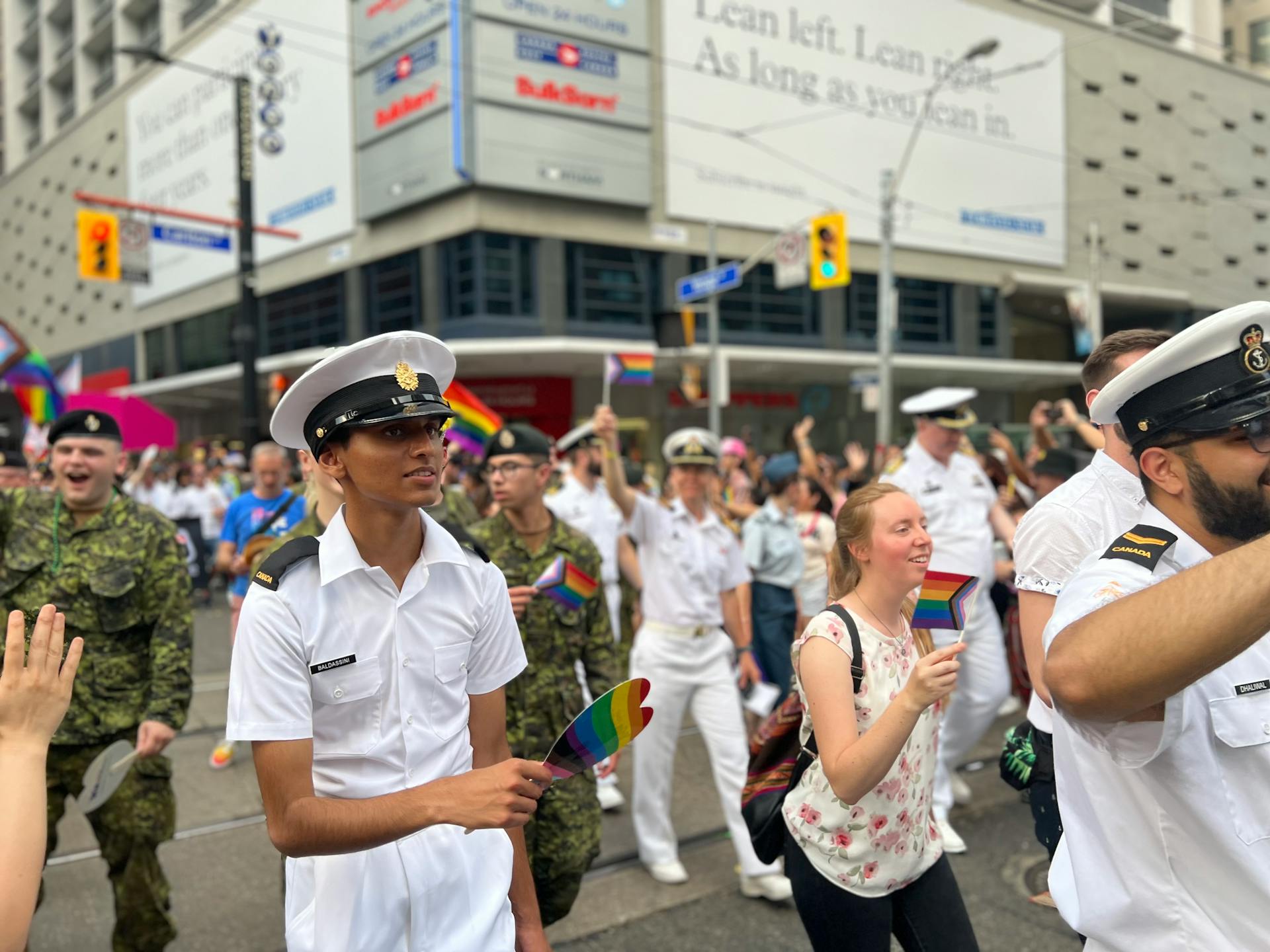 Military personnel and civilians celebrating diversity at a pride parade in an urban setting.