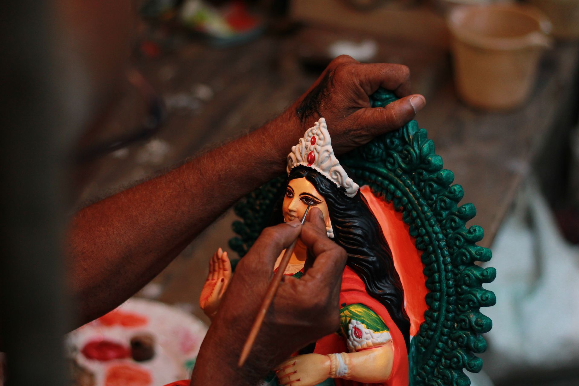 Close-up of an artist painting a traditional Indian figurine in Kolkata. Detailed craftsmanship.