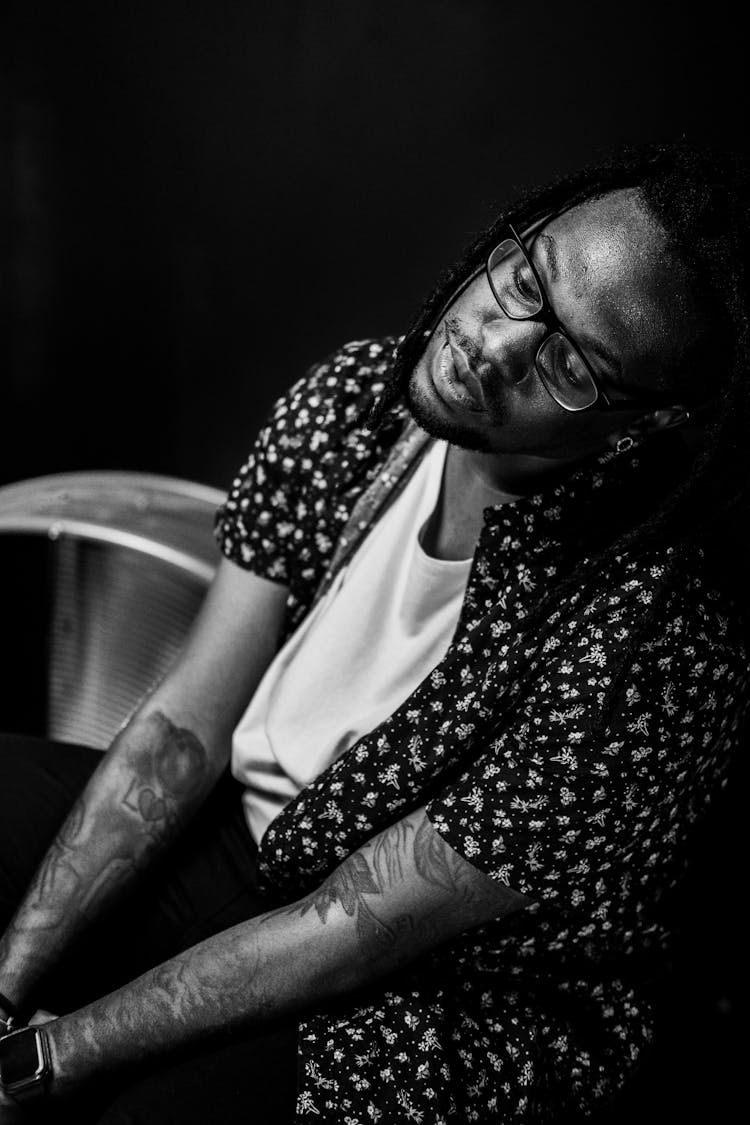 Man With Dreadlocks And Tattoos On Black Background