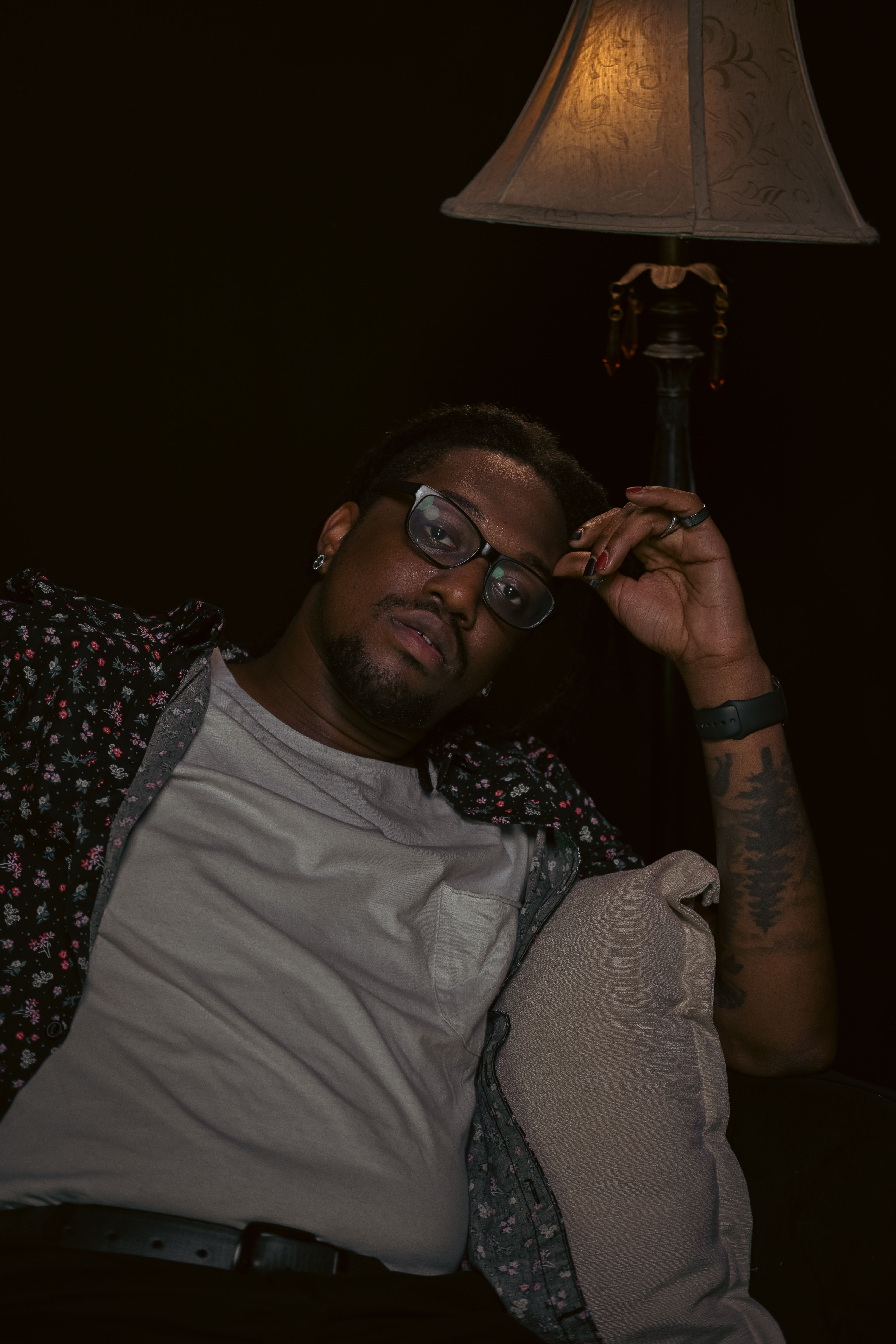 Portrait of a fashionable man wearing eyeglasses, relaxing indoors under warm lighting.