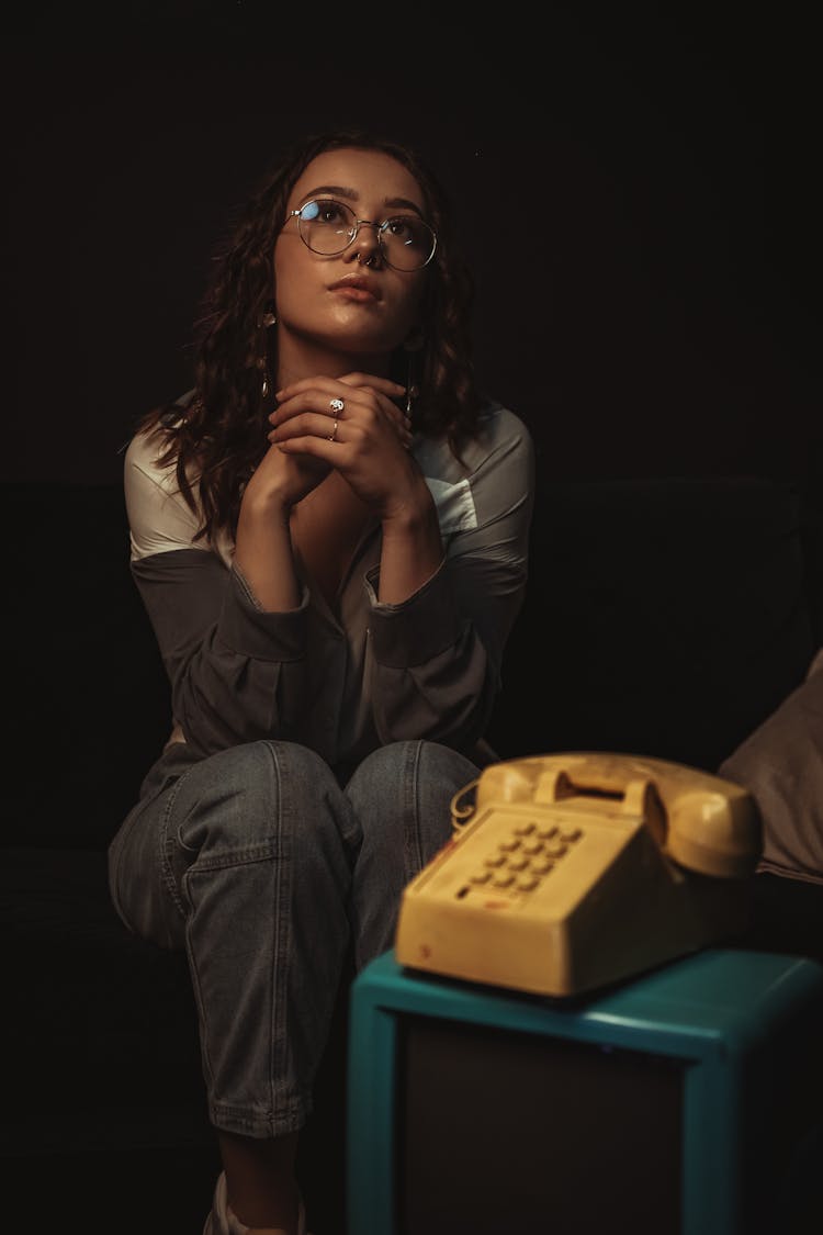 Young Woman Sitting In Front Of An Old-Fashioned Rotary Phone