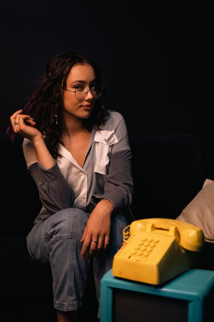 Young Woman Sitting In Front Of An Old-Fashioned Rotary Phone