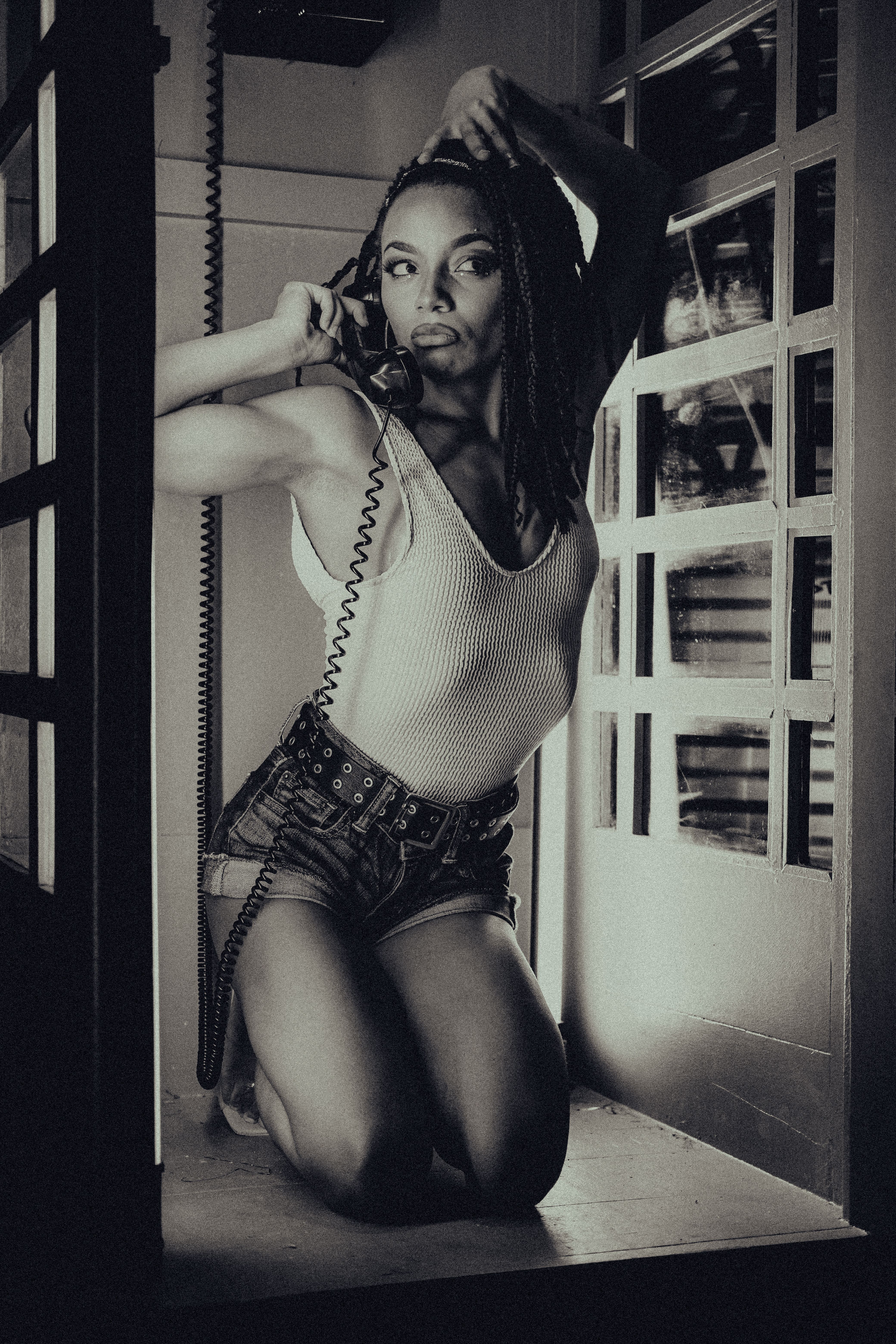 Grayscale Photo of a Woman in White Sleeveless Shirt Holding a Telephone