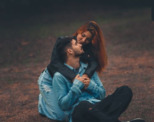 Free Loving couple embracing on a grassy field, sharing an affectionate moment. Stock Photo