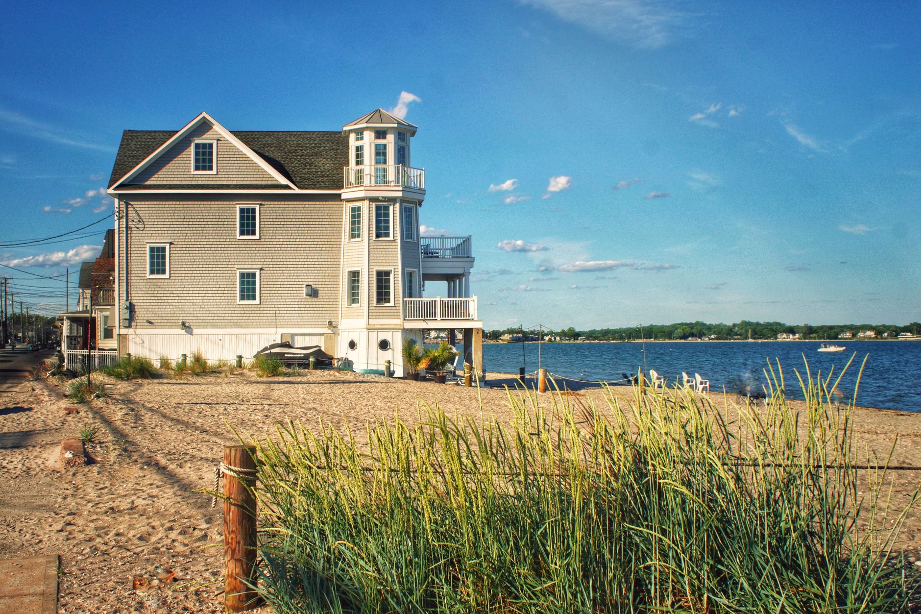 Beautiful coastal house in Milford, CT by the sandy beach during a sunny day.