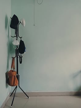 A coat rack with bags and face masks in a minimalist indoor corner with copy space.