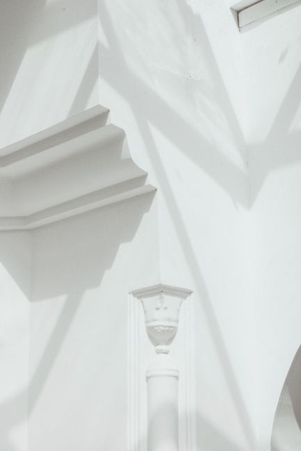 White interior wall with shadows highlighting classical architectural elements.
