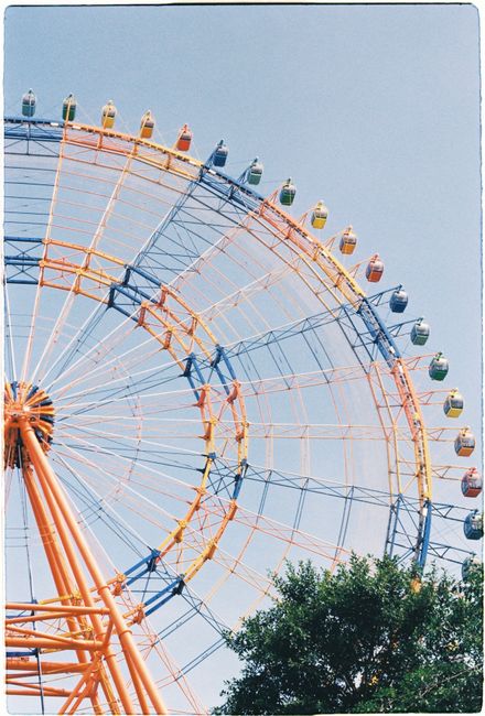 Captivating low-angle shot of a vibrant ferris wheel under a clear blue sky.