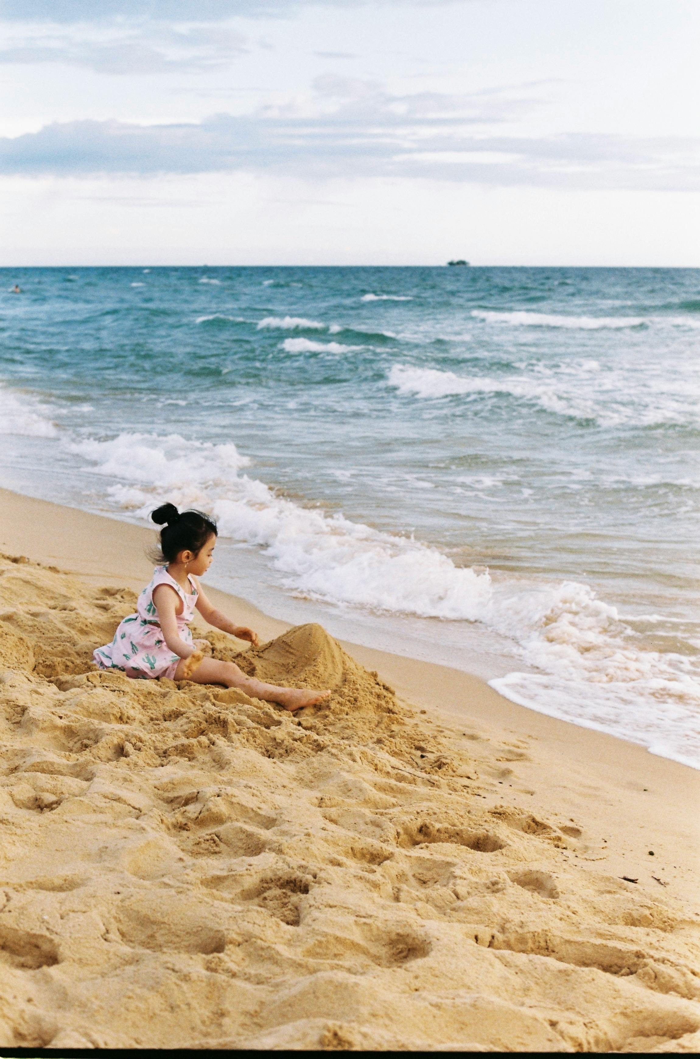 a young girl sitting on the beach sand