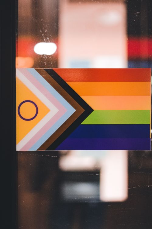 Free Progress Pride Flag displayed indoors, symbolizing LGBTQ+ inclusivity and diversity. Stock Photo