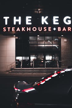 Nighttime view of The Keg Steakhouse + Bar entrance with neon lights.