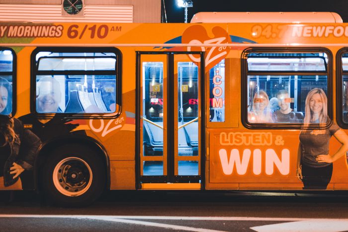 Orange city bus with a printed ad along its side