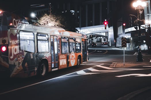 Urban night scene featuring a colorful public bus on city streets under glowing lights.