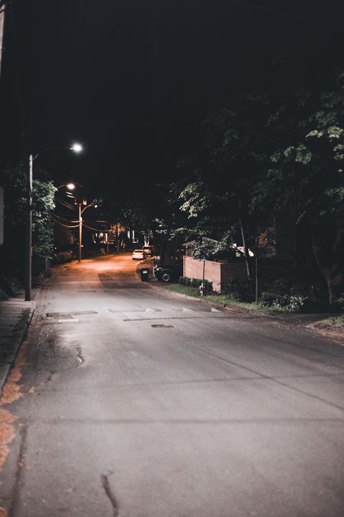Free A serene night scene of an empty residential street illuminated by streetlights. Stock Photo