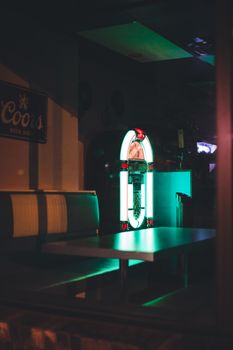 Cozy retro diner interior featuring a glowing jukebox at night, evoking nostalgia.