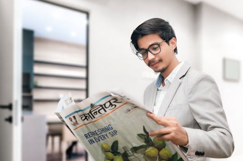 Free Man in Gray Suit Wearing Eyeglasses while Holding a Newspaper Stock Photo
