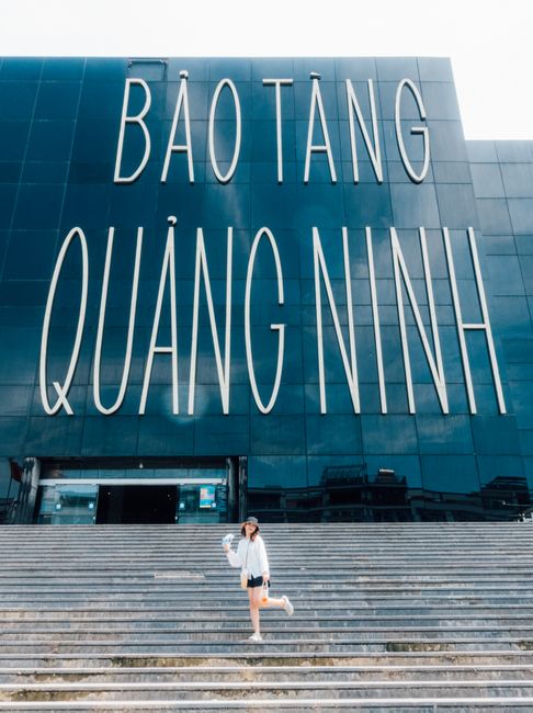 Woman at the entrance of Bảo Tàng Quảng Ninh, Vietnam. Modern architecture with bold signage.