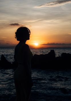 A silhouette of a woman standing by the sea at sunrise in Quảng Ninh, Vietnam.