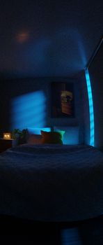 A dimly lit bedroom with neon blue lights and modern decor creates a calming nighttime atmosphere. — photo by Yusuf P